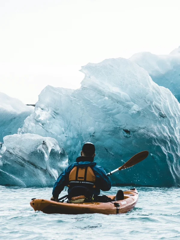 Kayaker paddling between icebergs